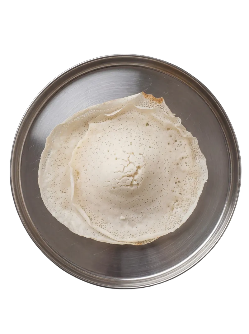 Kerala appam — bowl-shaped lacy rice crepe on a brass plate