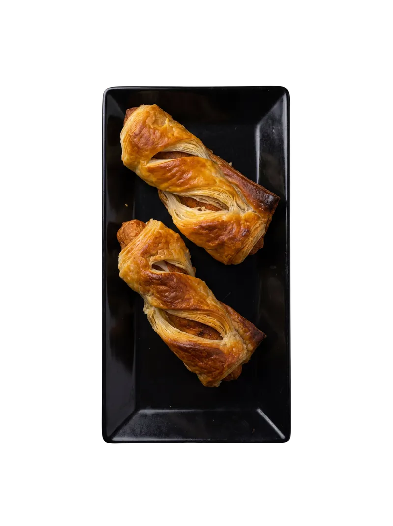 Two croissants on a long black rectangular plate photographed vertically with dramatic negative space