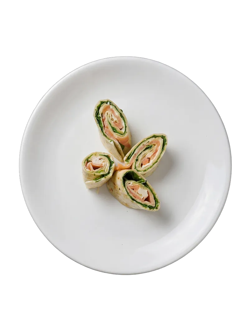 Sliced pinwheel wraps with colourful fillings arranged on a white plate