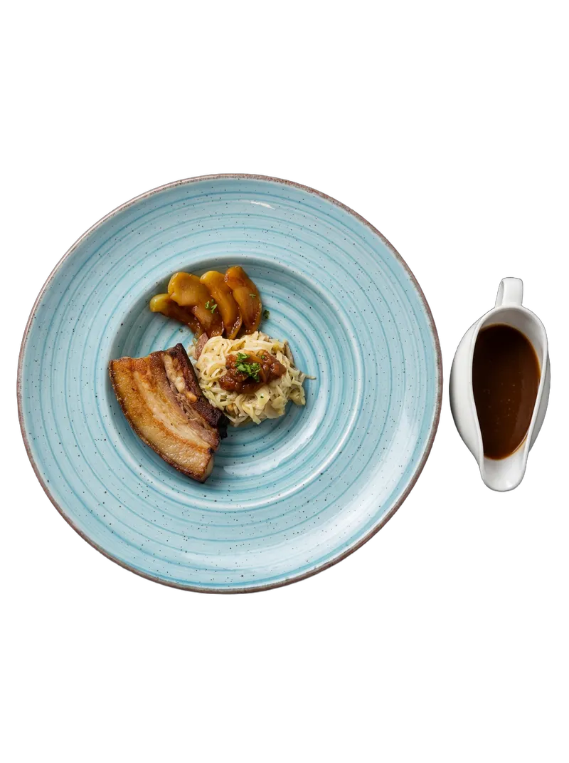 Crispy pork belly with ginger-scallion noodles and caramel apple on a wide sky-blue ceramic plate with a gravy boat
